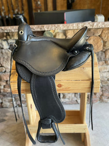 dp saddlery quantum short and light western with western dressage seat, side view on a wooden saddle rack