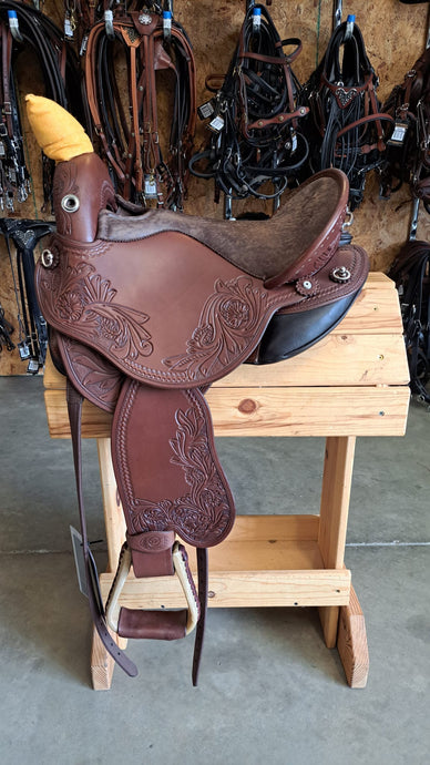 dp saddlery quantum short and light western with western dressage seat, side view on a wooden saddle rack, tack hanging on wall in the background