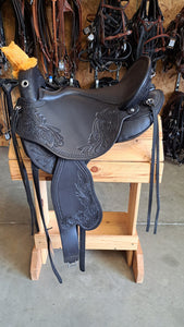 dp saddlery quantum short and light western with western dressage seat, side view on a wooden saddle rack, tack hanging on the wall in background