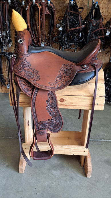 dp saddlery quantum short and light western with a western dressage seat, side view on a wooden saddle rack, horse tack in background