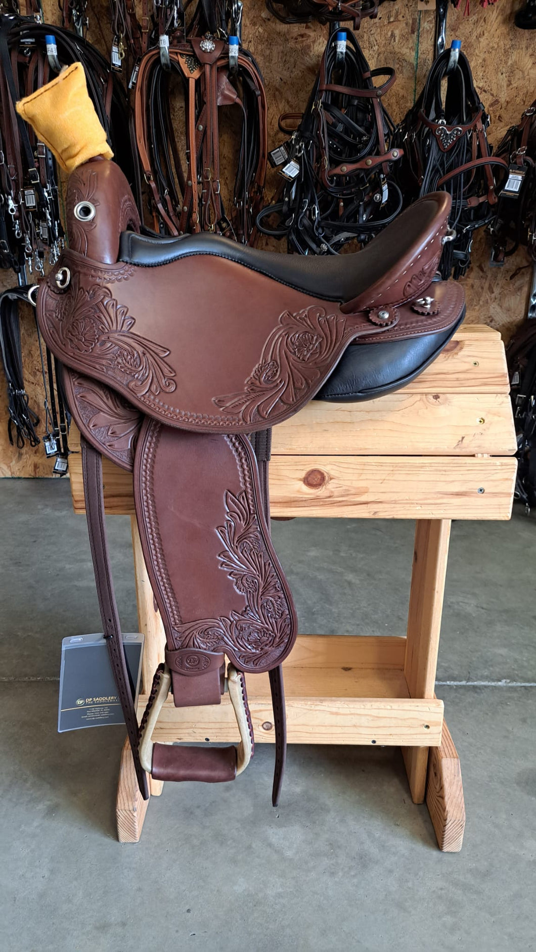 dp saddlery quantum short and light western with a western dressage seat 6324, side view on a wooden saddle rack, horse tack in the background