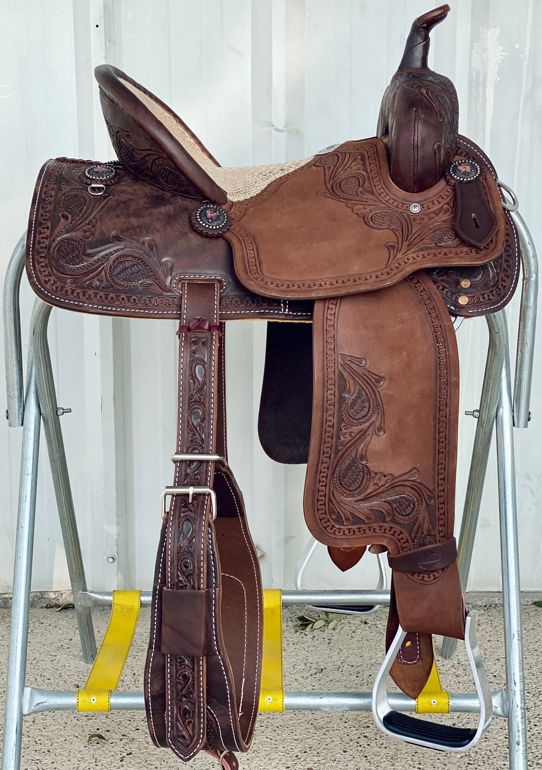 alamo saddlery medusa barrel saddle, side view on a metal saddle rack