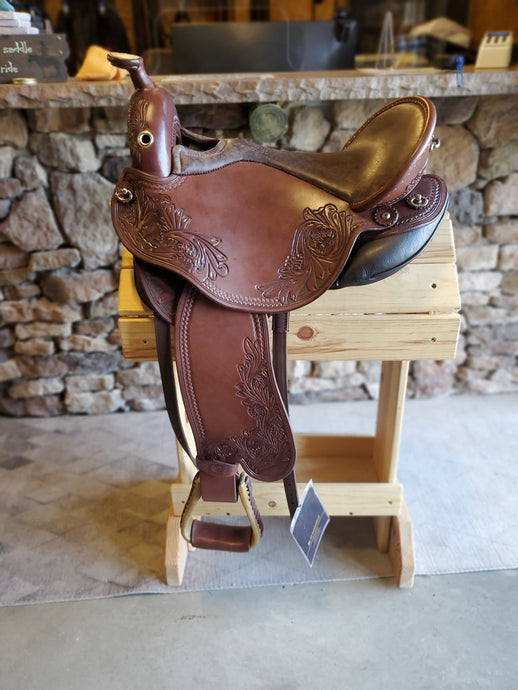 dp saddlery quantum short and light western with a western dressage seat 5505, side view on a wooden saddle rack 